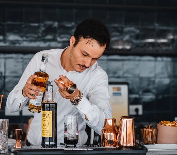Food truck & Pizzeria a Potenza Picena Barista versa liquore in un misurino di rame al bar moderno