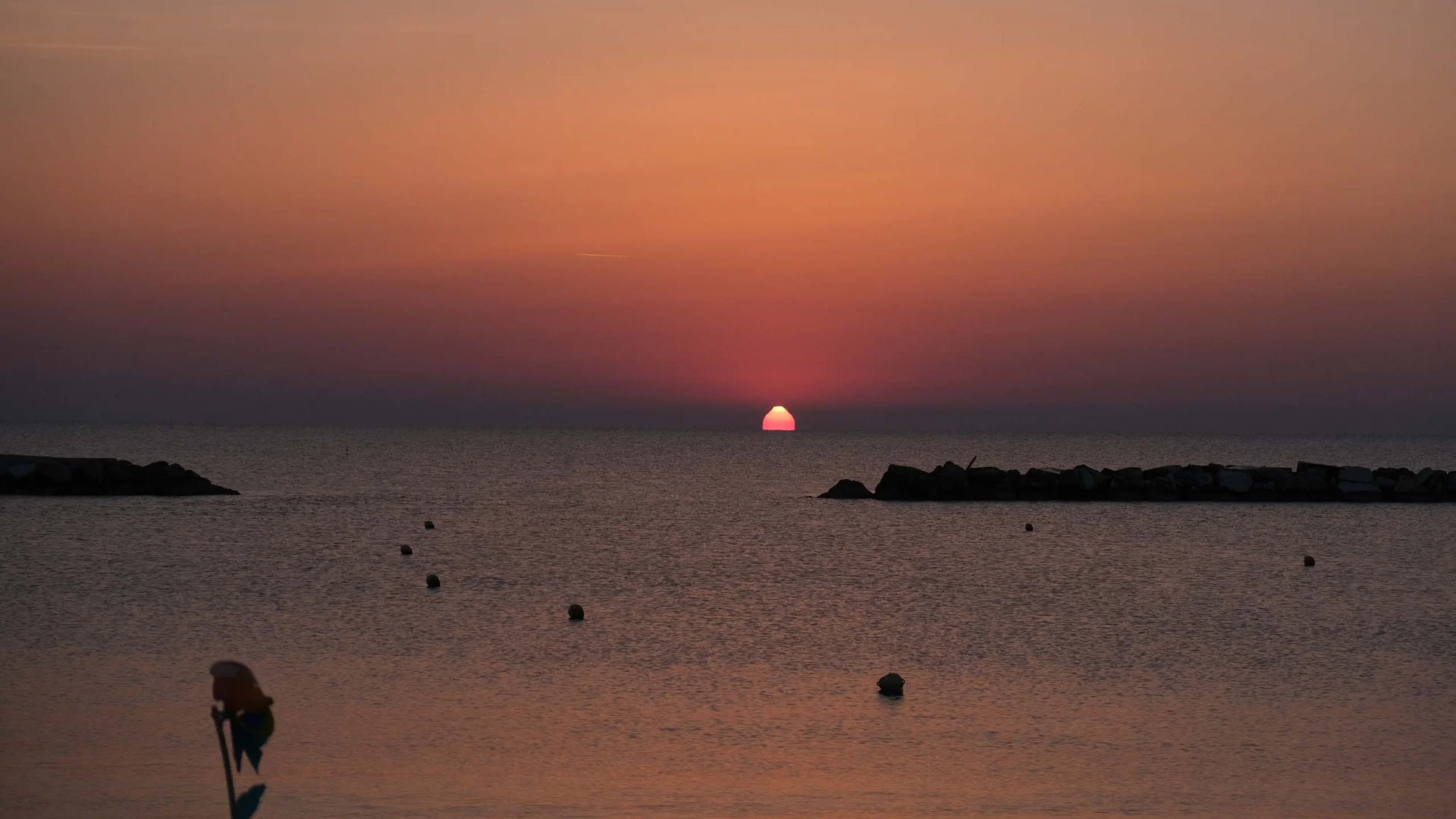 Riviera del Conero: le spiagge più belle Tramonto sul mare con sole che sfiora l'orizzonte e cielo arancione