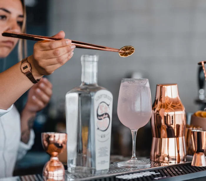 Food truck & Pizzeria a Potenza Picena Bartender che decora cocktail con fetta di limone essiccato usando pinze