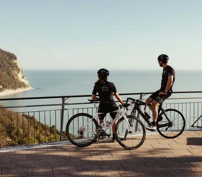 Un family hotel al Conero? Meglio un resort! Due ciclisti con bici da corsa guardano il mare da un belvedere panoramico