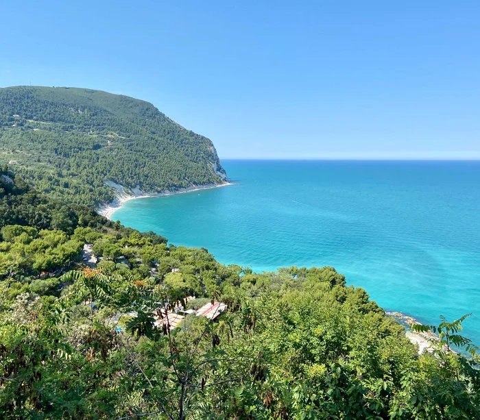 Una vacanza nelle Marche: terra di emozioni Costa verde con mare turchese e cielo azzurro limpido in una giornata soleggiata