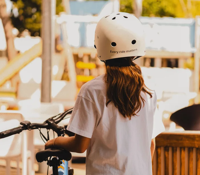 Vacanza in e-bike nelle Marche Ragazza con casco bianco e bici, vista posteriore