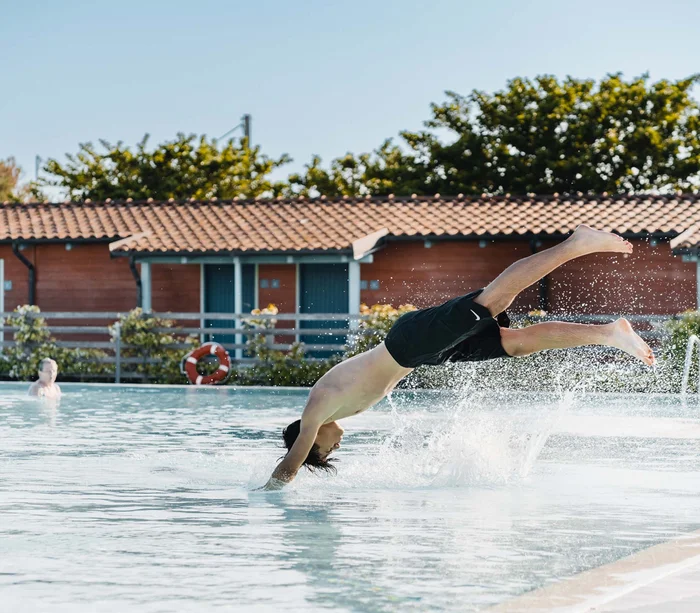 Villaggio nelle Marche sul mare con piscina Ragazzo che fa un tuffo a mani avanti in piscina all'aperto