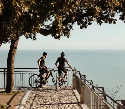Un family hotel al Conero? Meglio un resort! Due ciclisti in abbigliamento sportivo guardano il mare da un belvedere