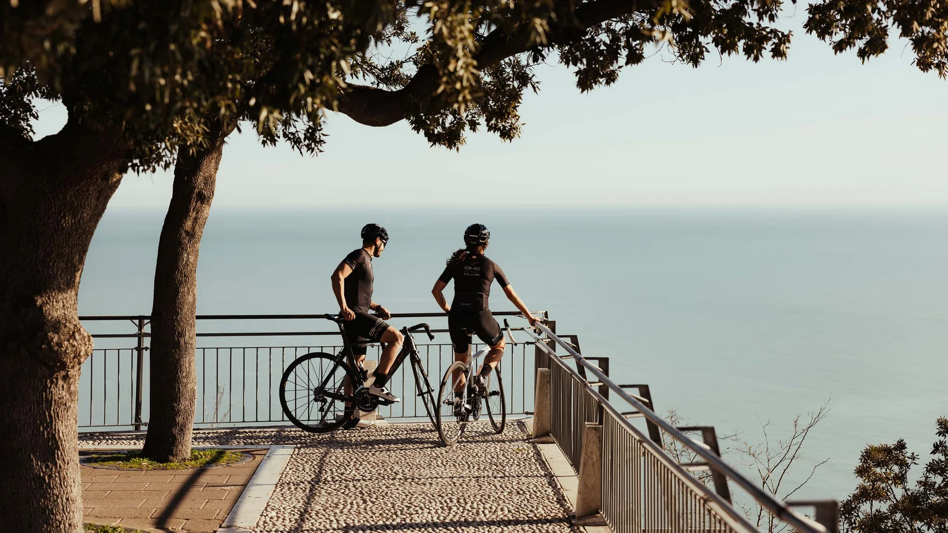 Dai monti al mare: le vostre avventure nelle Marche Due ciclisti in abbigliamento sportivo guardano il mare da un belvedere