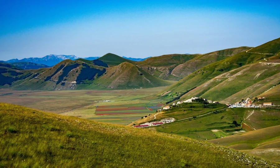Resort al mare: pronti per un’escursione sul Conero? Paesaggio montano verde con villaggio e cielo azzurro