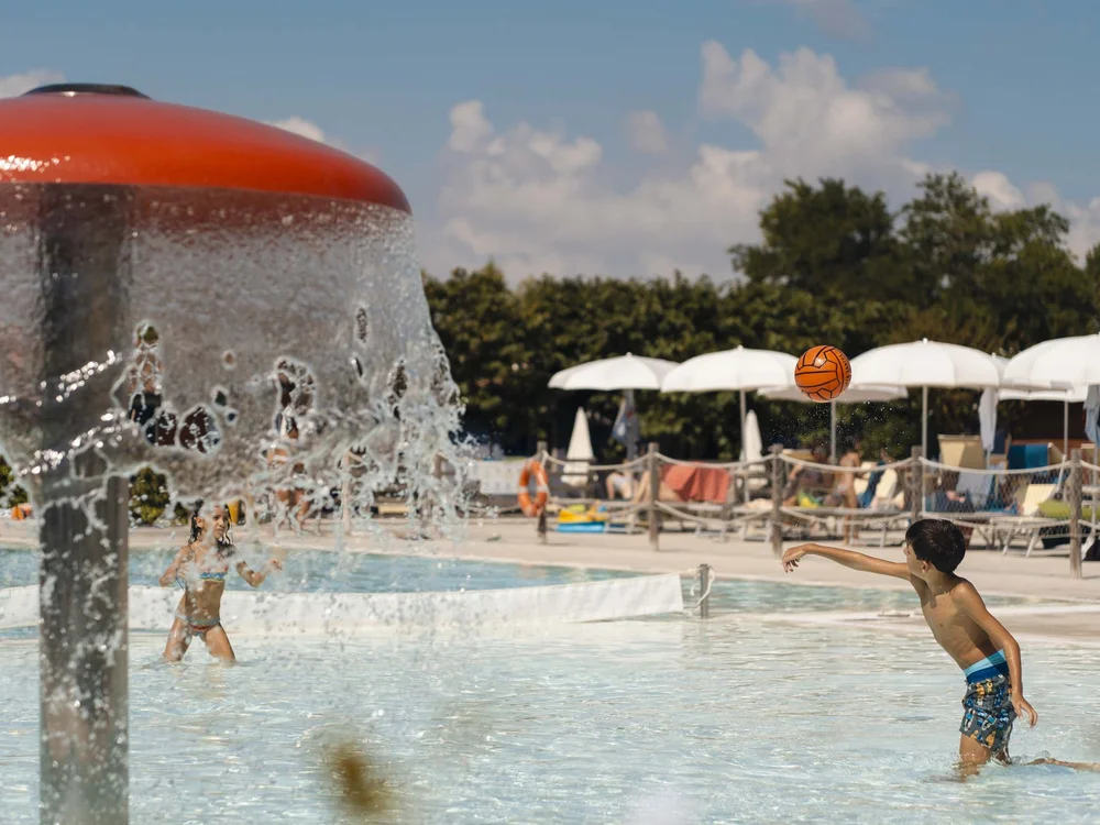 Benvenuti nel nostro resort al Conero Bambini che giocano con palla in una piscina all'aperto con fontana d'acqua