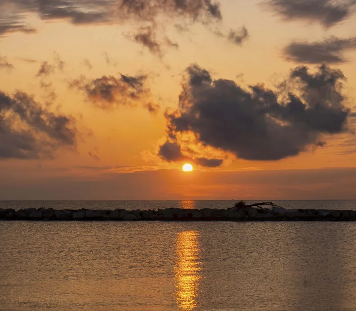 Riviera del Conero: le spiagge più belle Tramonto sul mare con nuvole scure e riflesso dorato sull'acqua