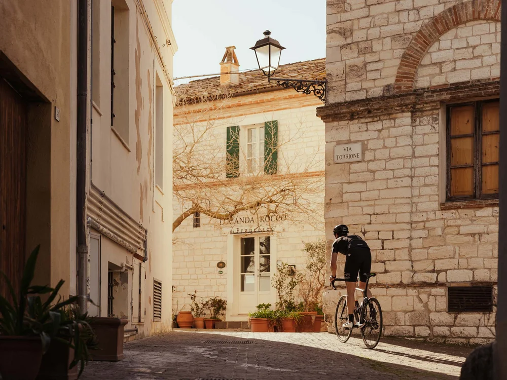 Gli eventi al Natural Village Resort Ciclista che pedala in una strada di ciottoli in un villaggio storico