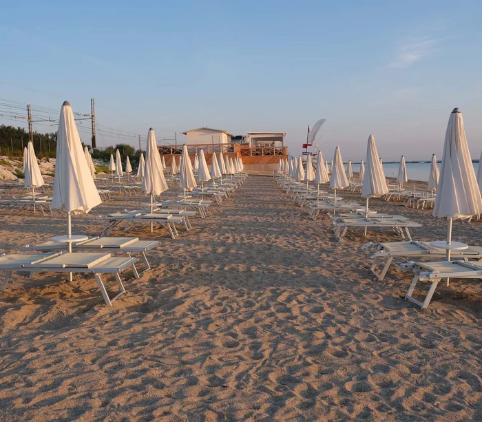 Riviera del Conero: le spiagge più belle Ombrelloni e lettini chiusi su una spiaggia deserta al tramonto