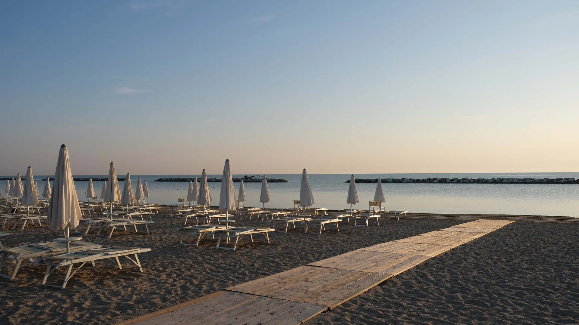 Riviera del Conero: le spiagge più belle Spiaggia deserta con ombrelloni chiusi e sdraio all'alba o al tramonto