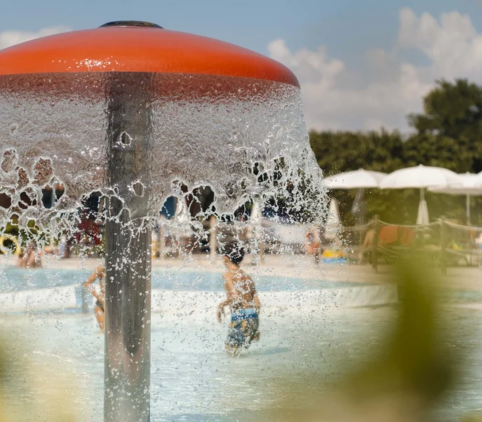 Villaggio nelle Marche sul mare con piscina Acqua che scende da una fontana a forma di fungo in piscina con bambini che giocano