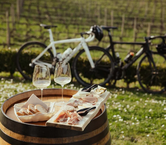 Una vacanza nelle Marche: terra di emozioni Vino bianco, tagliere di salumi e pane su botte all'aperto con due bici