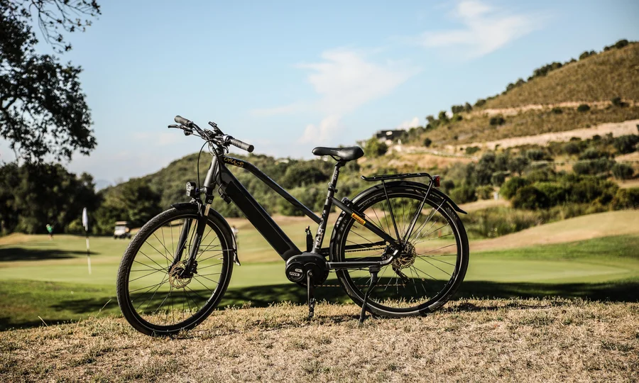 Resort al mare: pronti per un’escursione sul Conero? Bicicletta elettrica nera su prato con colline sullo sfondo.