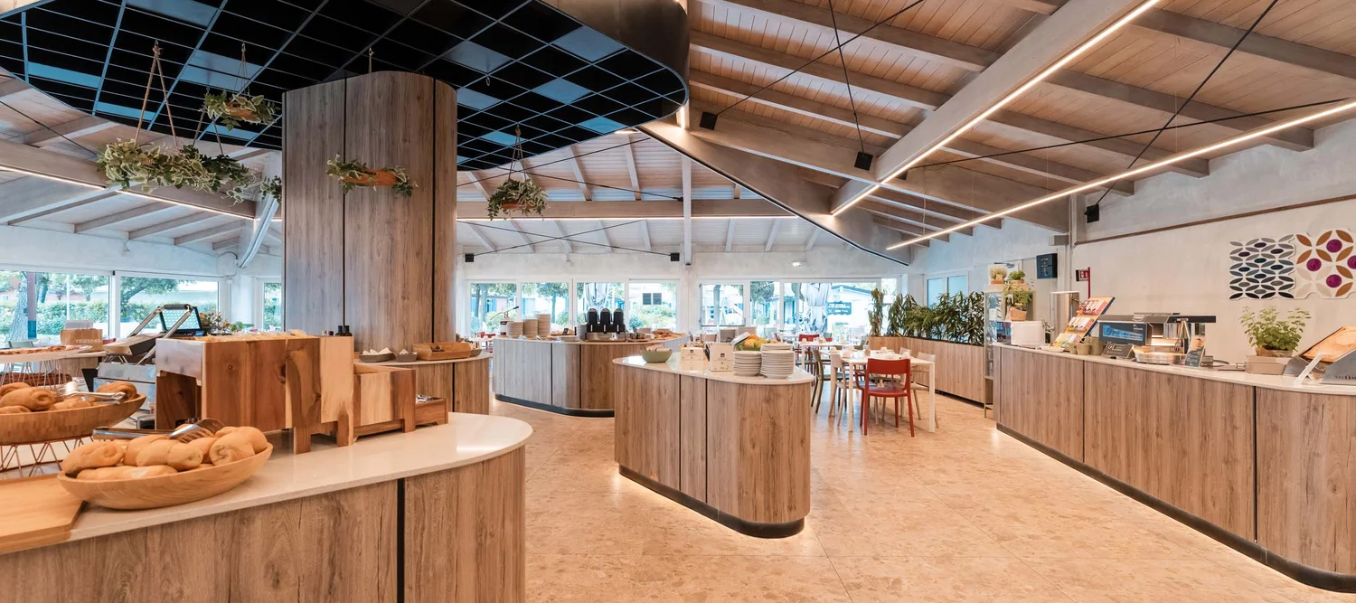 Garden Restaurant: uno dei ristoranti del nostro resort Interno moderno di un ristorante con buffet in legno e decorazioni con piante