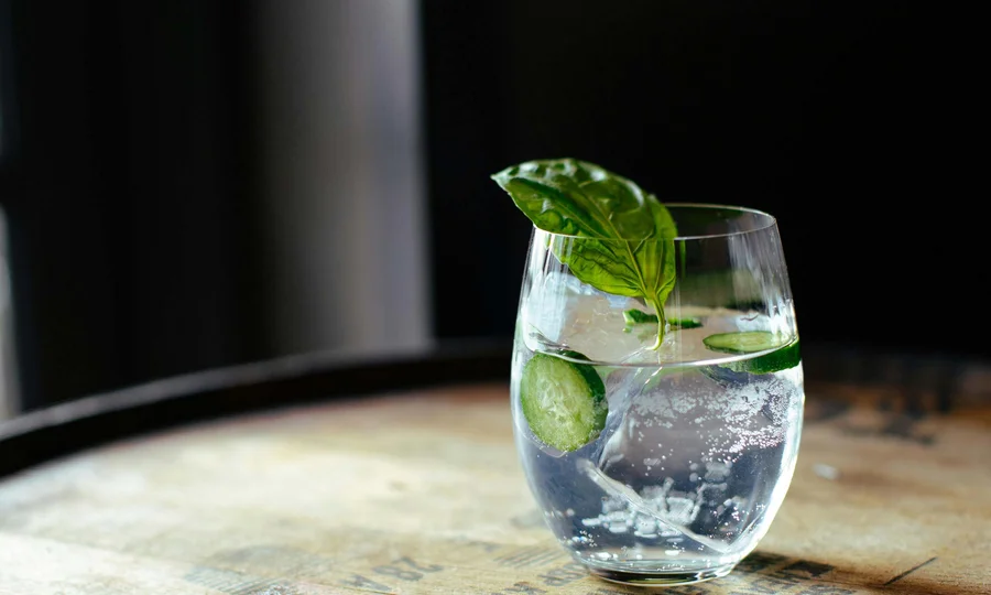 Resort al mare: pronti per un’escursione sul Conero? Bicchiere con acqua frizzante, fette di cetriolo e foglia di basilico