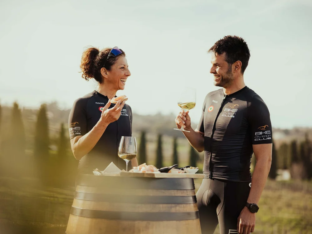 Un weekend romantico nelle Marche Due ciclisti si godono vino e snack all'aperto con paesaggio collinare
