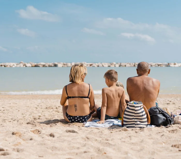 Riviera del Conero: le spiagge più belle Famiglia seduta sulla spiaggia con vista sul mare e scogliere distanti