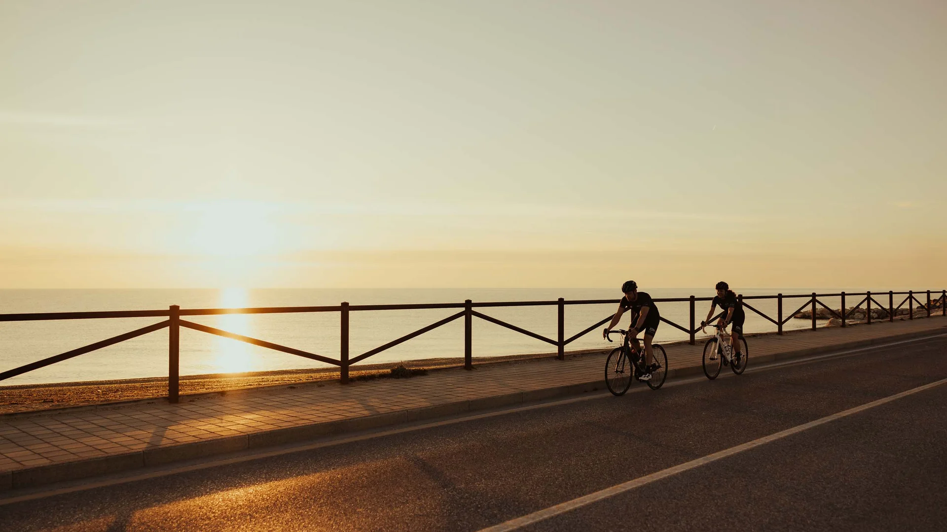 Una vacanza nelle Marche: terra di emozioni Due ciclisti in bicicletta al tramonto lungo una strada costiera
