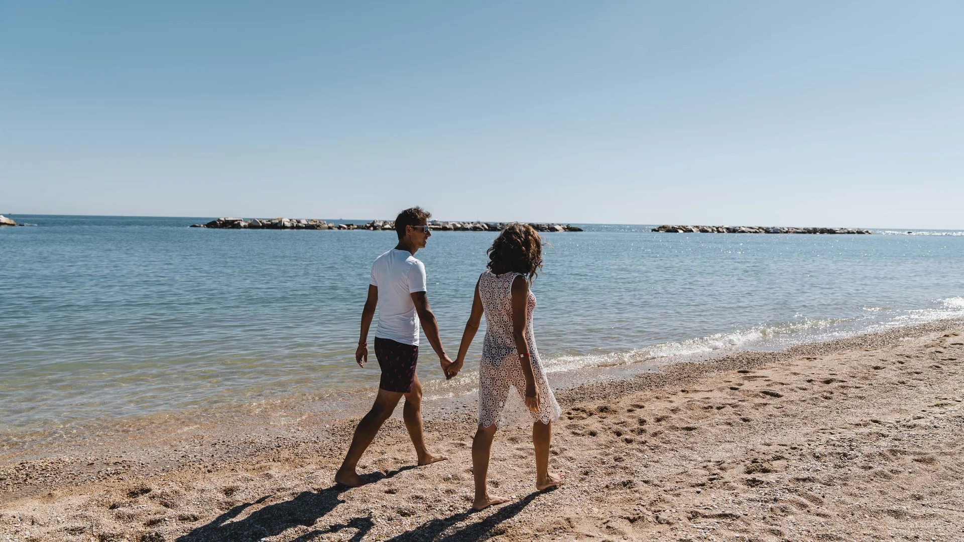 Un weekend romantico nelle Marche Coppia che cammina mano nella mano sulla spiaggia soleggiata