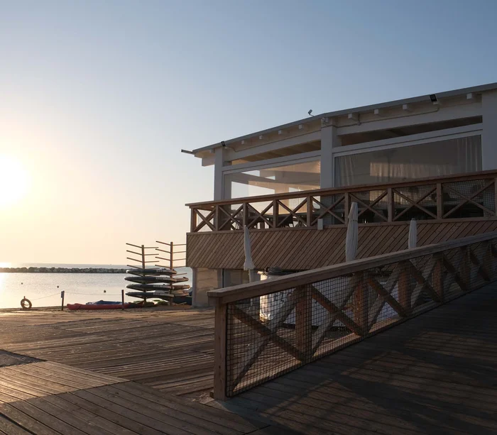 Riviera del Conero: le spiagge più belle Tramonto sul mare con struttura in legno e kayak impilati sulla spiaggia