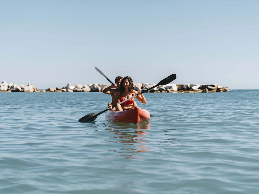 Escursioni in barca al Conero e molto altro Coppia che va in kayak sull'acqua con rocce sullo sfondo