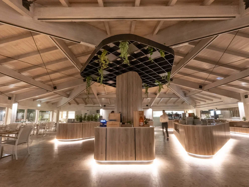 Garden Restaurant: uno dei ristoranti del nostro resort Interno moderno di un ristorante con illuminazione calda e arredi in legno