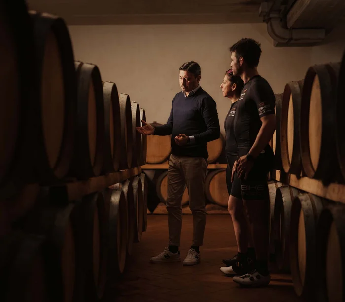 Una vacanza nelle Marche: terra di emozioni Persone in cantina tra botti di legno per la conservazione del vino