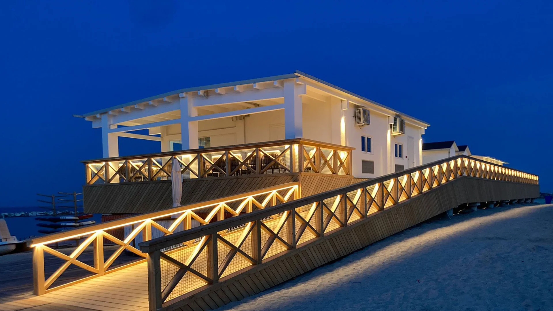 Le specialità culinarie delle Marche e del NVR Rampa illuminata che conduce a edificio bianco sulla spiaggia di notte