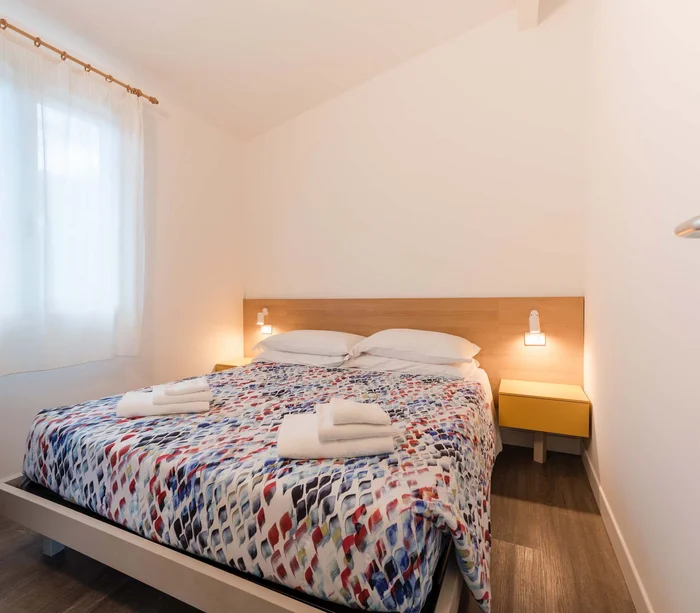Una vacanza al mare sul Conero Camera da letto con letto matrimoniale e asciugamani bianchi piegati