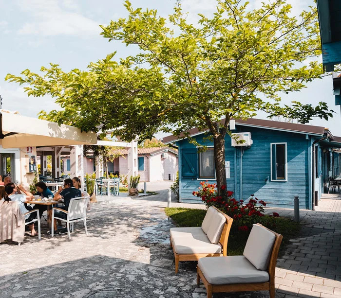 Food truck & Pizzeria a Potenza Picena Persone che mangiano all'aperto vicino a case di legno blu e panchine