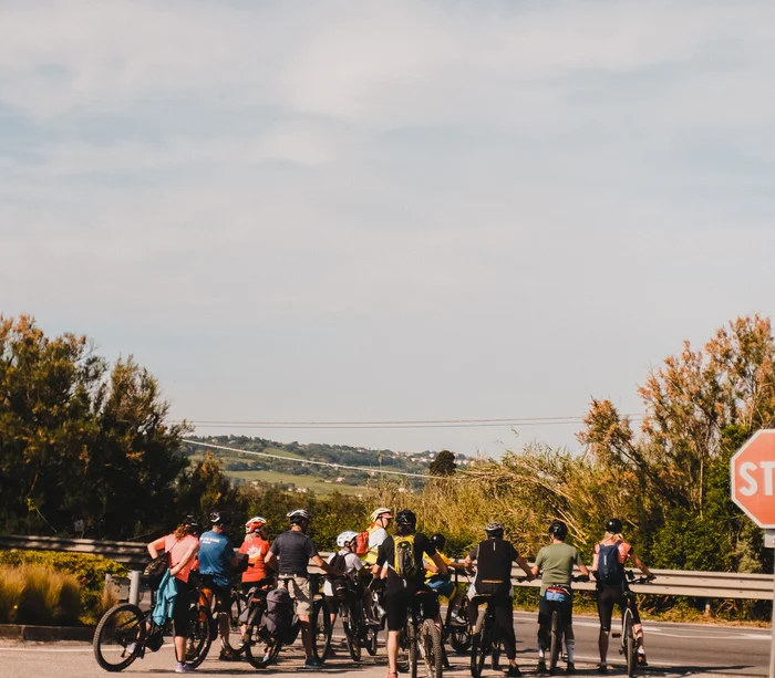 Vacanza in e-bike nelle Marche Gruppo di ciclisti fermi vicino a un cartello stop in una strada di campagna