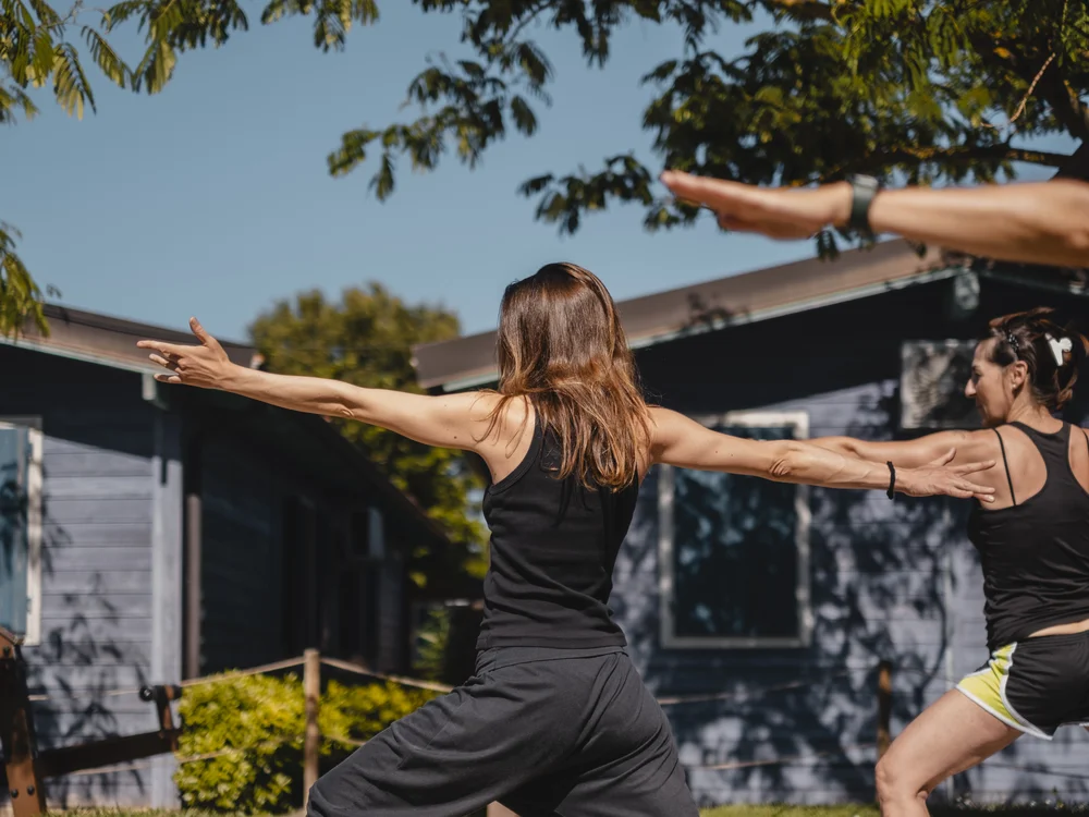 Gli eventi al Natural Village Resort Due donne che fanno yoga all'aperto in un giardino soleggiato