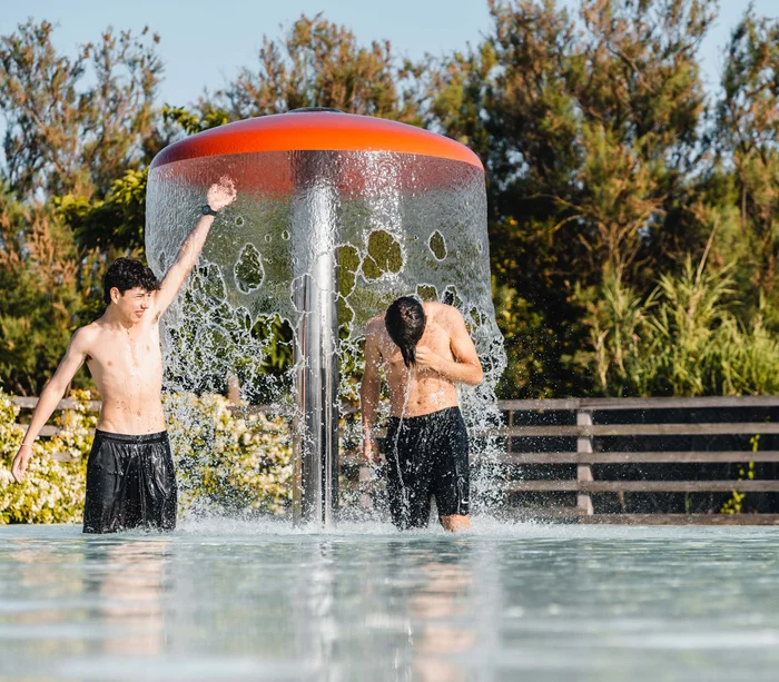 Villaggio nelle Marche sul mare con piscina Due ragazzi si rinfrescano sotto una cascata d'acqua in piscina all'aperto