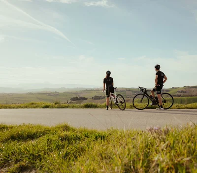 Un family hotel al Conero? Meglio un resort! Due ciclisti in tenuta nera guardano il paesaggio collinare da una strada