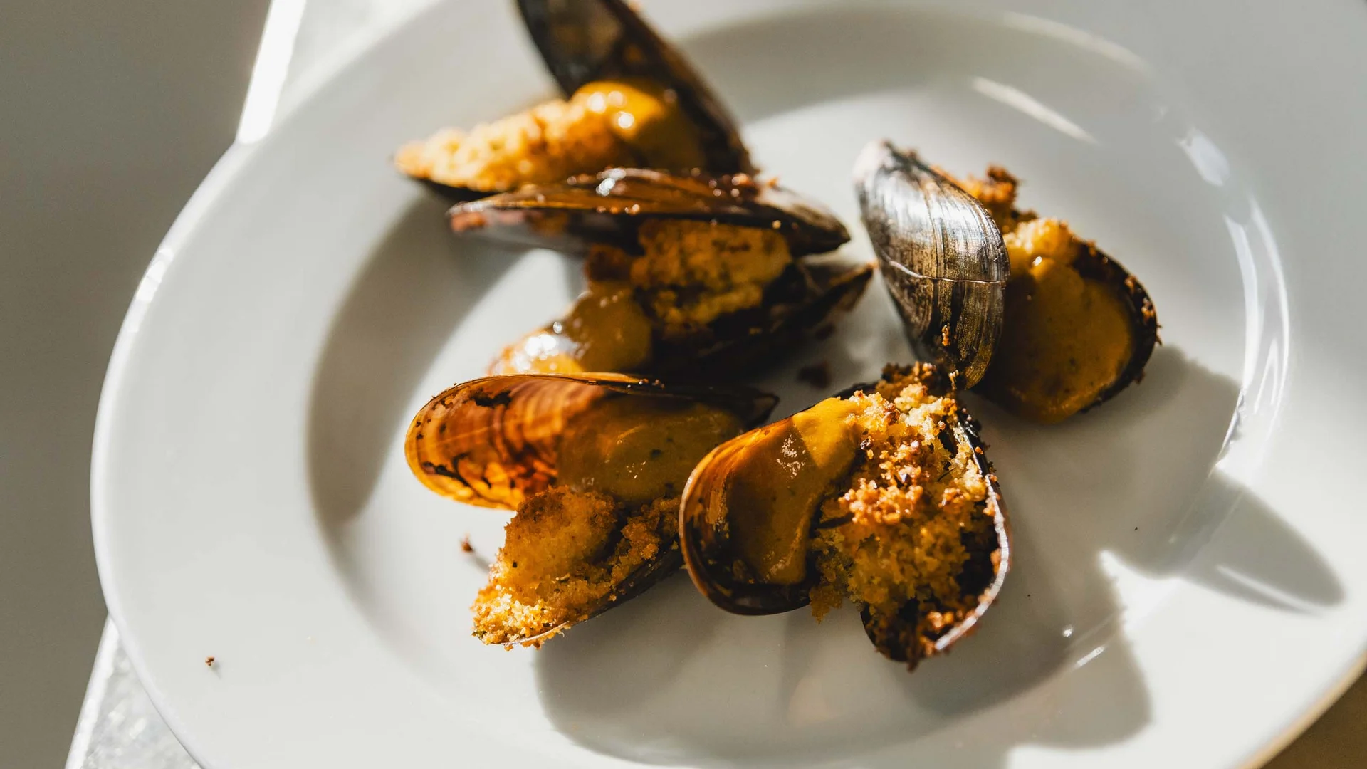 Le specialità culinarie delle Marche e del NVR Cozze gratinate con pane tostato e salsa su piatto bianco