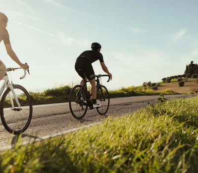 Un family hotel al Conero? Meglio un resort! Due ciclisti in abbigliamento nero pedalano su strada in campagna al tramonto