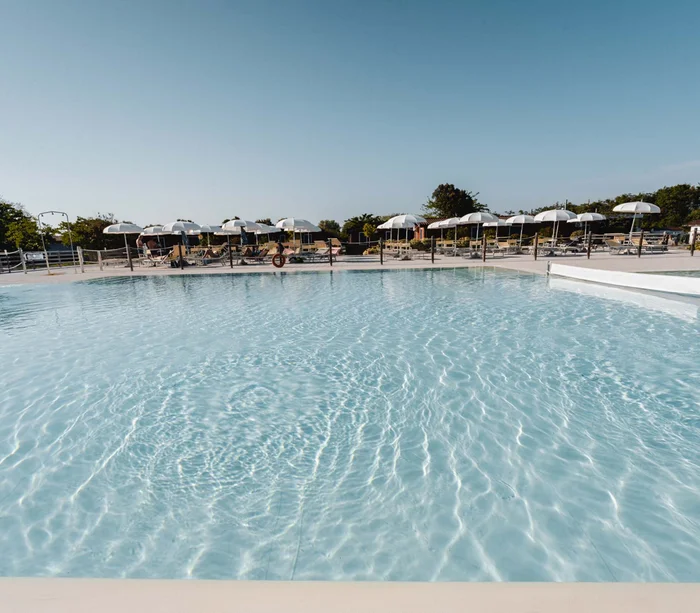 Villaggio nelle Marche sul mare con piscina Piscina all'aperto con ombrelloni bianchi e lettini in una giornata di sole