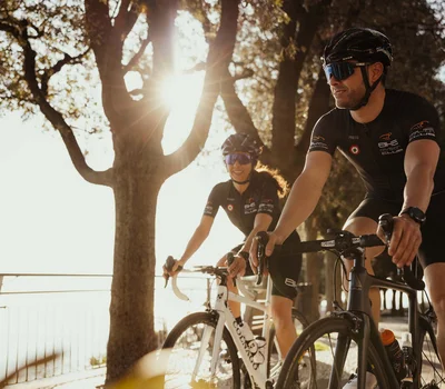 Un family hotel al Conero? Meglio un resort! Due ciclisti in abbigliamento da corsa pedalano al sole vicino a un albero