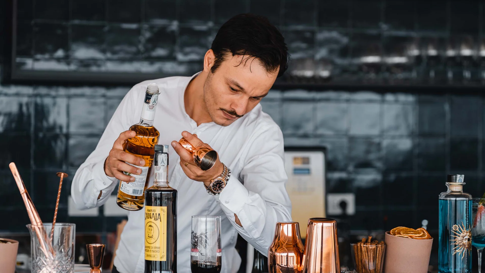 Seaside restaurant & lounge bar in the Marche region Bartender pouring liquor into a copper jigger at a modern bar