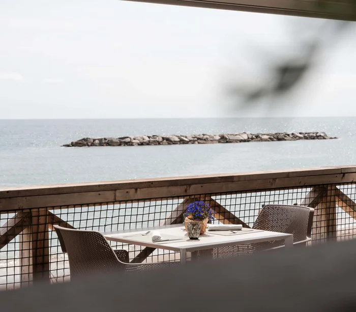 Un villaggio nelle Marche sul mare: il Natural Village Resort Tavolo apparecchiato e vista sul mare da una terrazza con balaustra in legno