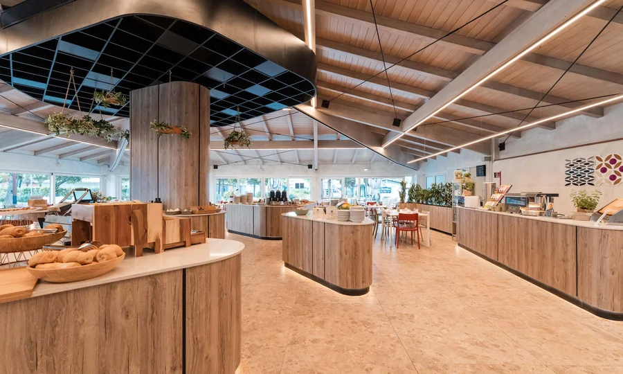 Un villaggio nelle Marche sul mare: il Natural Village Resort Interno moderno di un ristorante con buffet in legno e decorazioni con piante