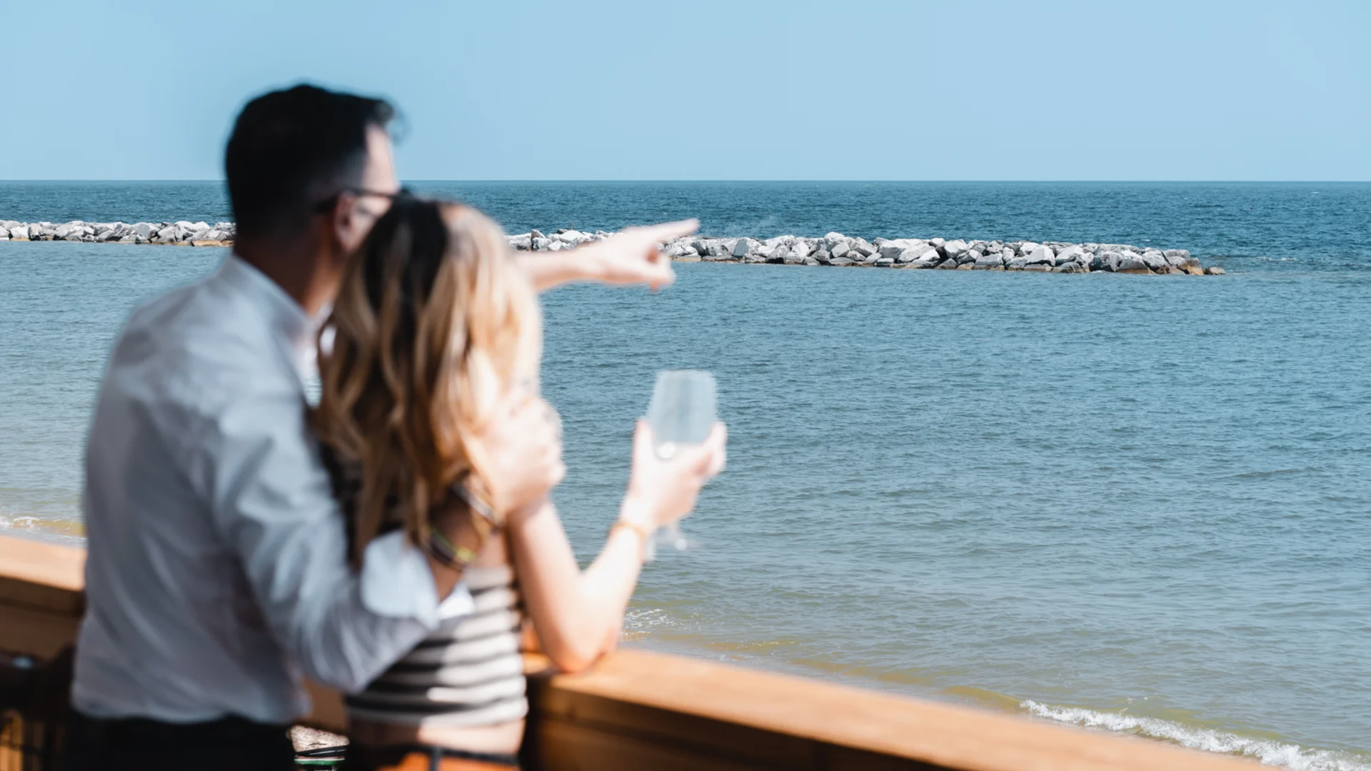 Un villaggio nelle Marche sul mare: il Natural Village Resort Coppia che guarda e indica il mare da una terrazza di legno