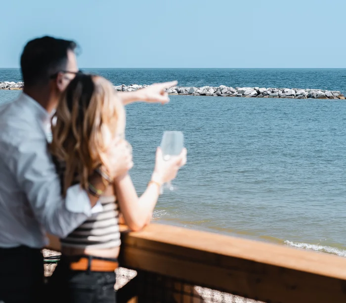 Un villaggio nelle Marche sul mare: il Natural Village Resort Coppia che guarda e indica il mare da una terrazza di legno