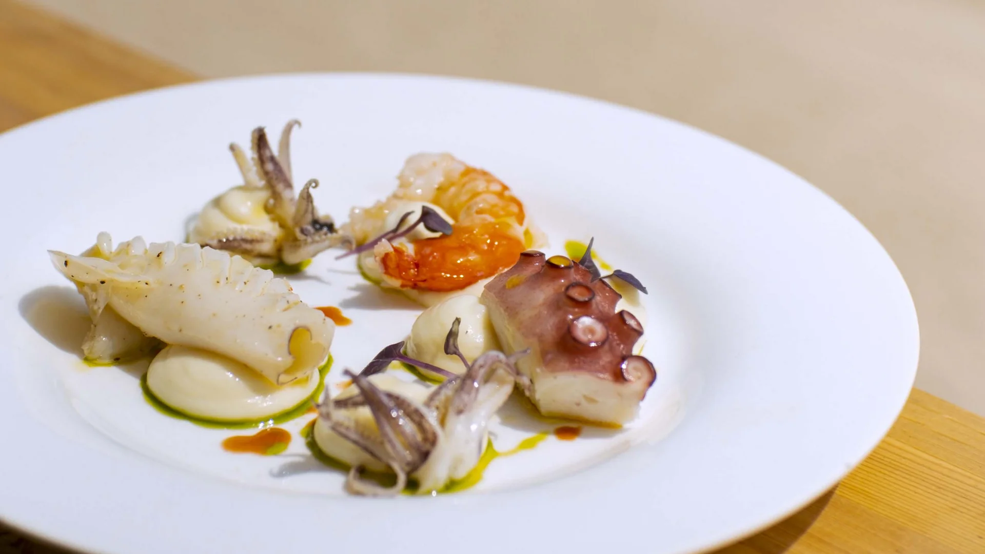 Seaside restaurant & lounge bar in the Marche region Plate of seafood with octopus, shrimp, and squid on white cream
