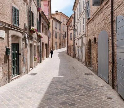 Un villaggio nelle Marche sul mare: il Natural Village Resort Strada acciottolata tra edifici in mattoni con persiane e fiori alle finestre