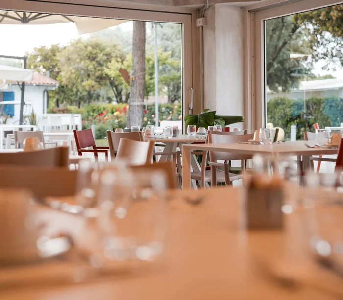 Un villaggio nelle Marche sul mare: il Natural Village Resort Interno di ristorante con tavoli apparecchiati e vista sul giardino