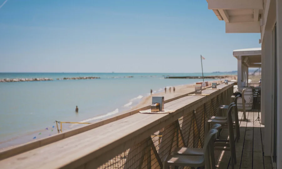 Seaside restaurant & lounge bar in the Marche region Balcony by the sea with chairs overlooking the sunny beach
