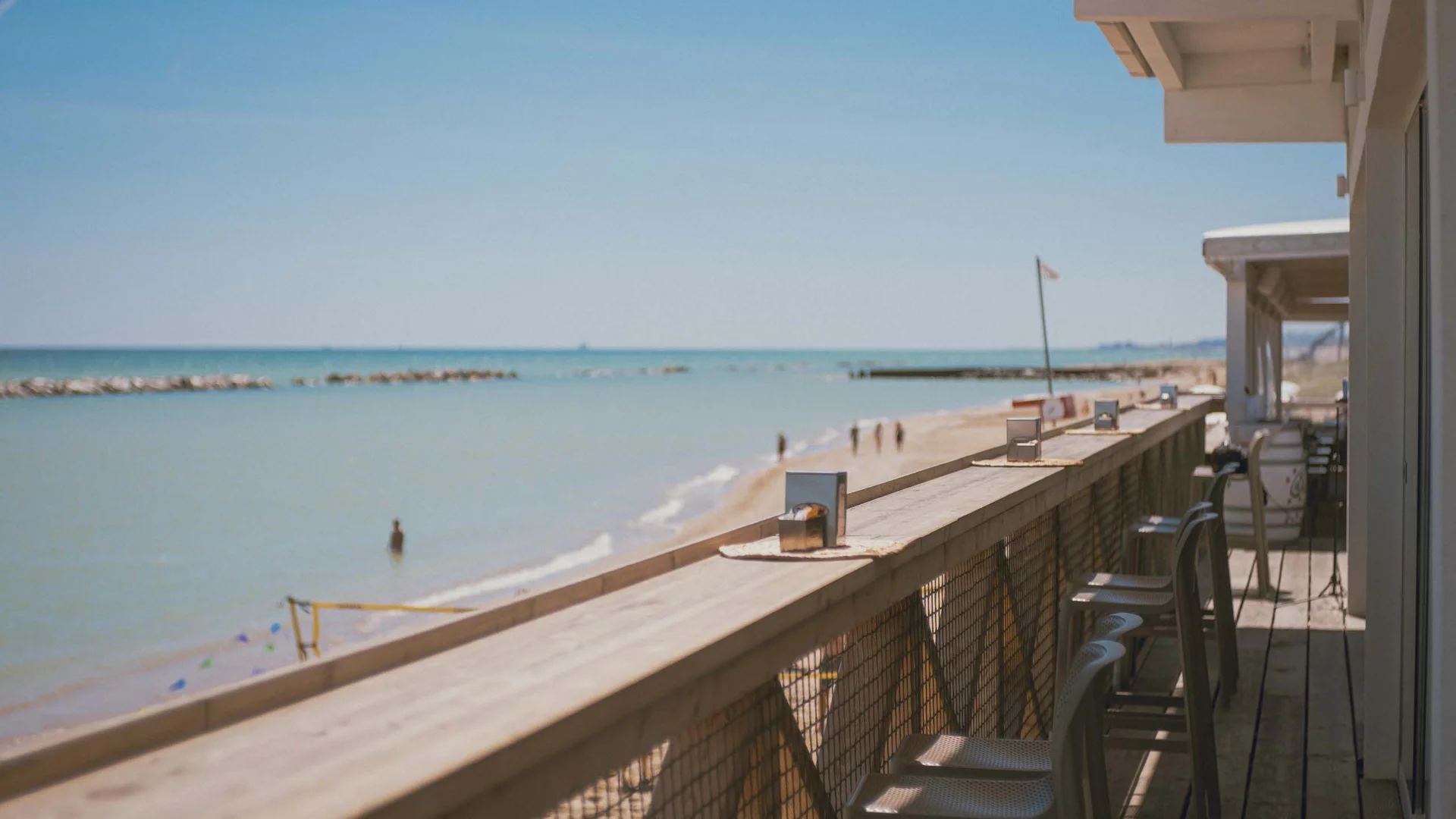Seaside restaurant & lounge bar in the Marche region Balcony by the sea with chairs overlooking the sunny beach