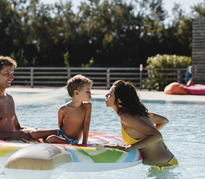 Un villaggio nelle Marche sul mare: il Natural Village Resort Famiglia in piscina con bambino su gonfiabile a forma di ghiacciolo